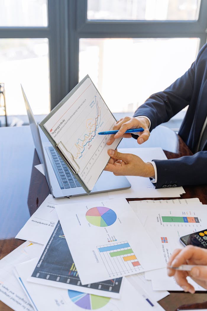 about-us-01 Business professionals discussing financial graphs and charts in an office setting.